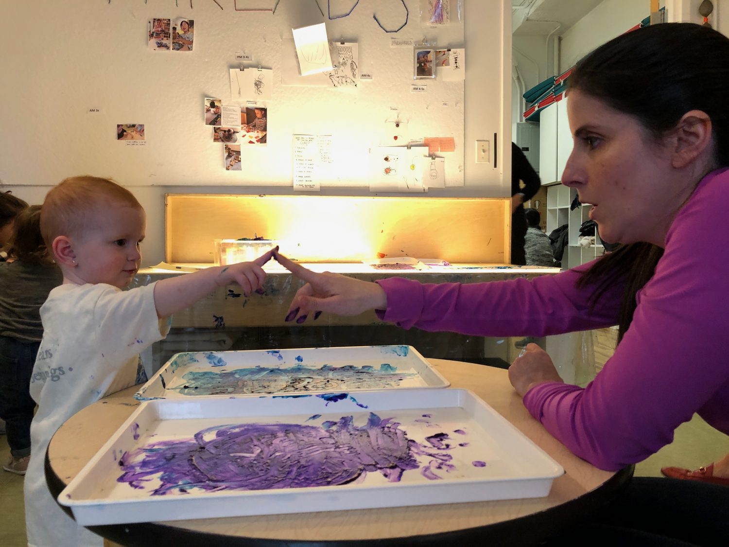 A daughter and mother touching fingers covered in paint