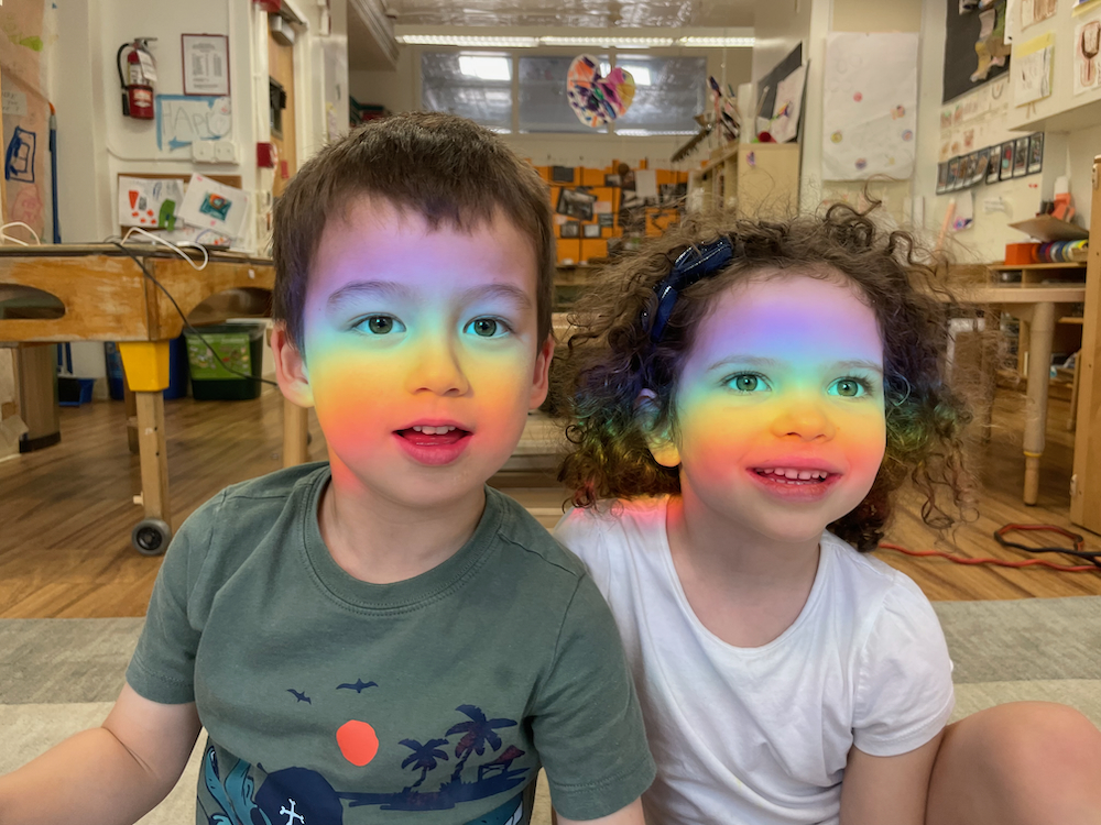 Children looking with a rainbow going over their face
