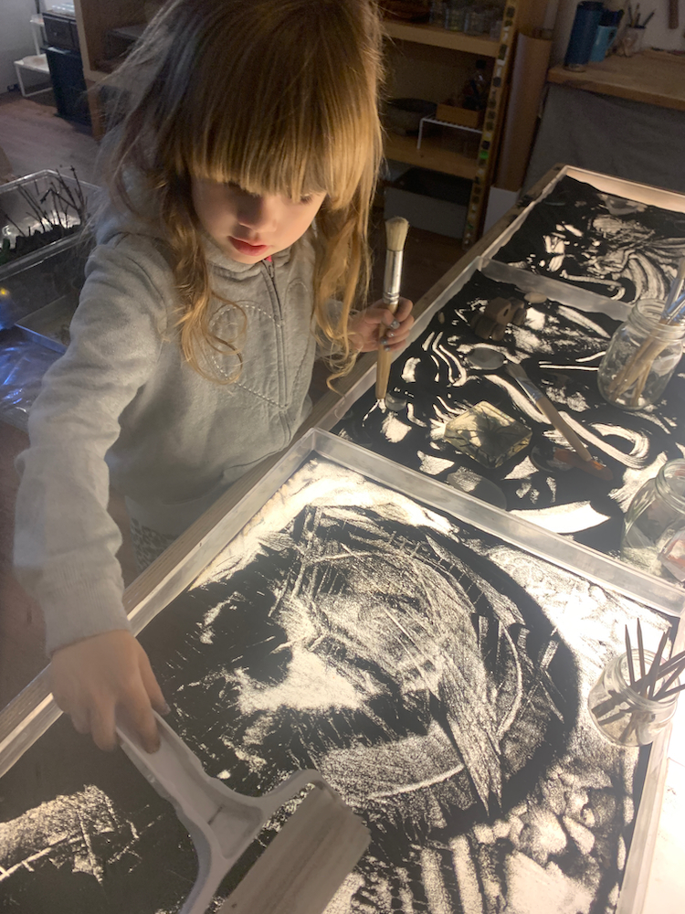 a child playing with sand on a light table