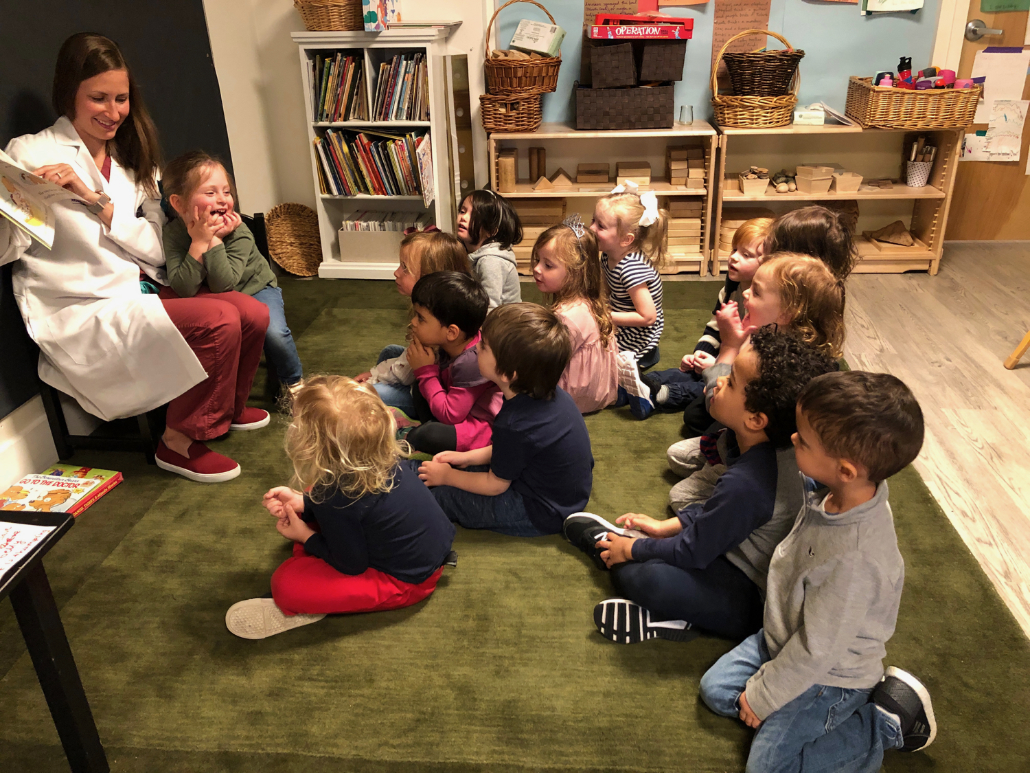 a mother reading a book to the class in her doctor scrubs