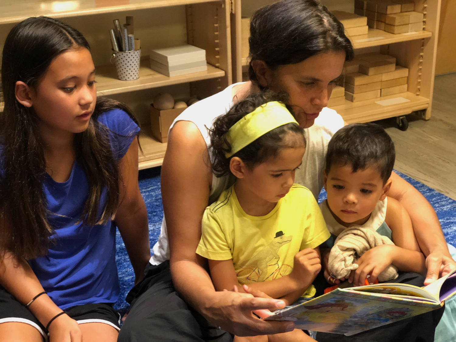 a mother reading with her three children in the classroom