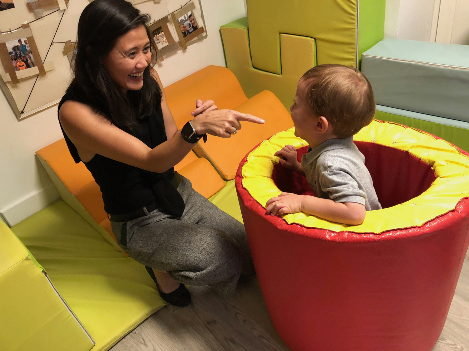 a parent playing and pointing to a laughing child