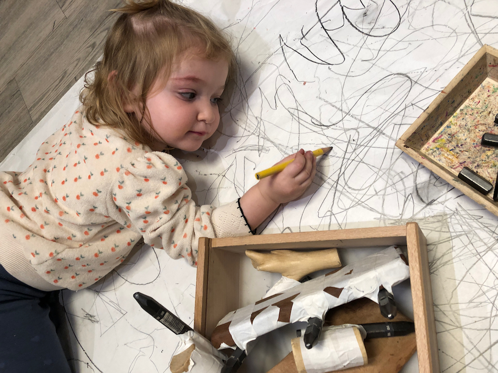 Child drawing with charcoal on the floor