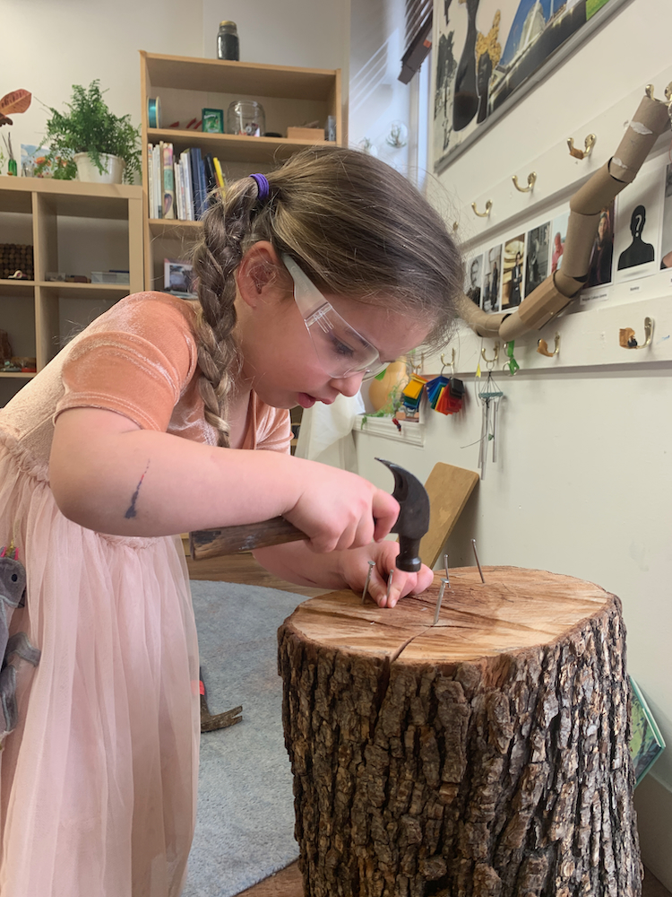 a child hammering nails into a wood stump