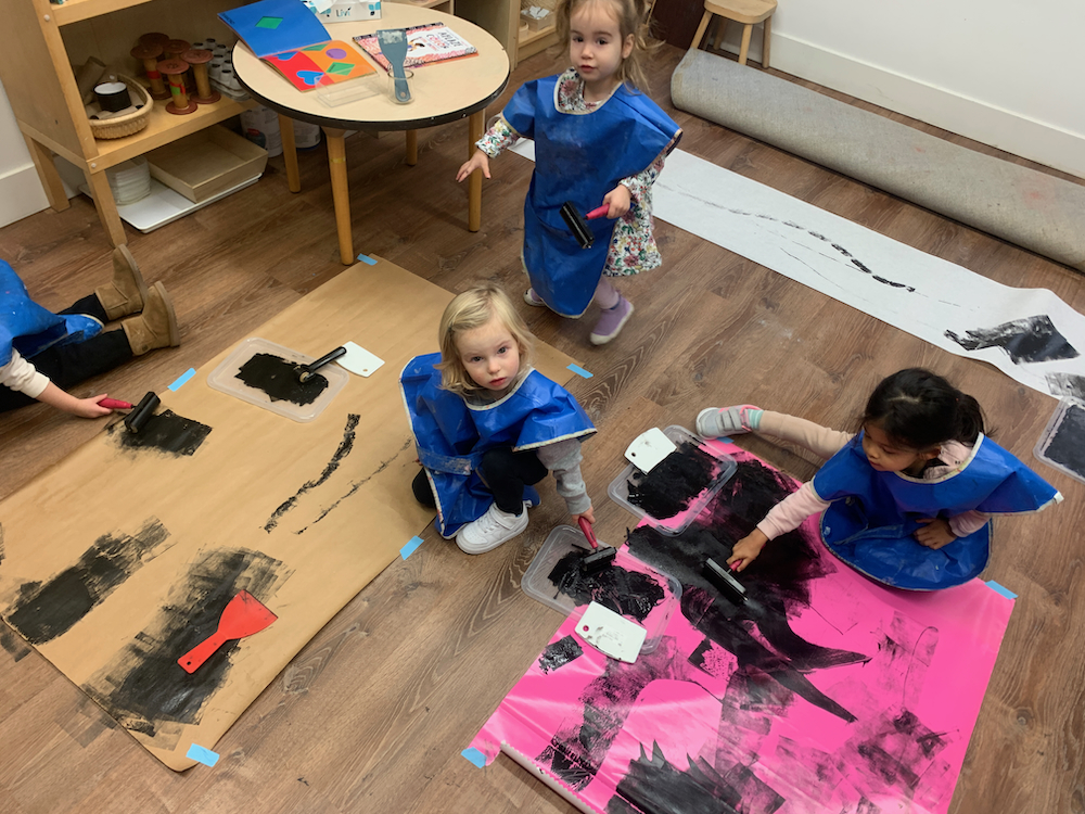 Children rolling paint on paper on floor