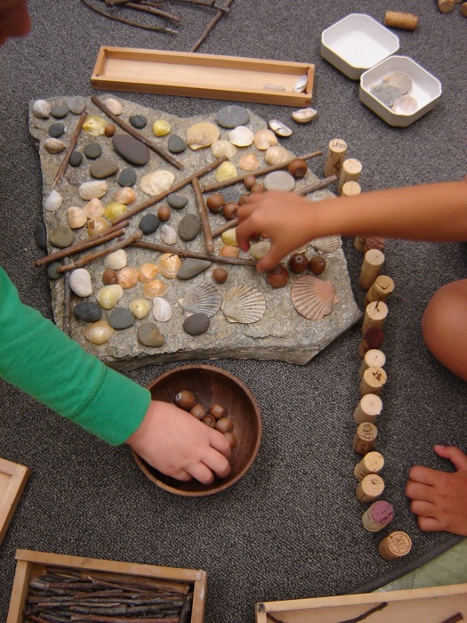 Children making art composition with sticks, stones and water