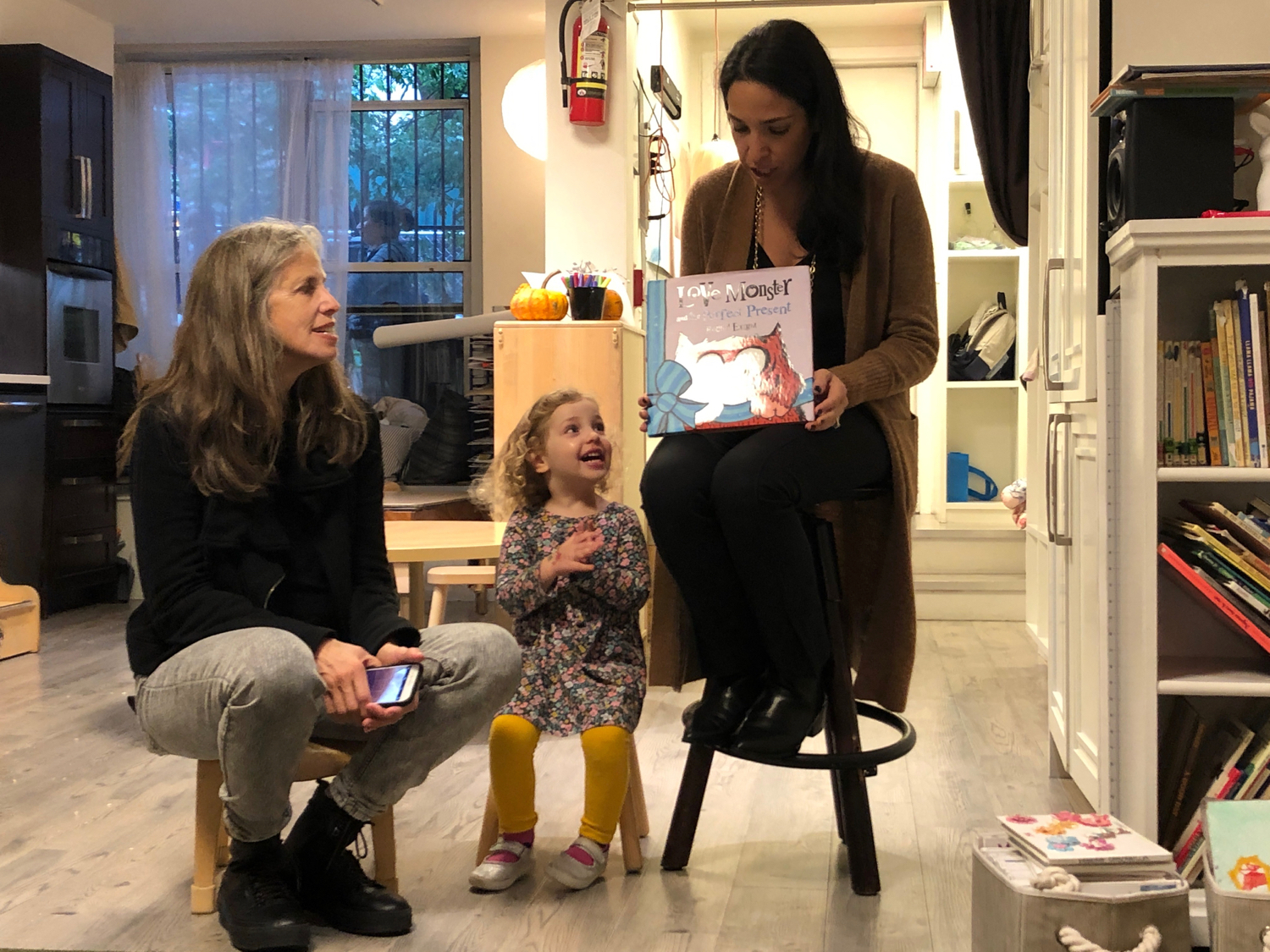 a child cheering as a mother and grandmother read to her